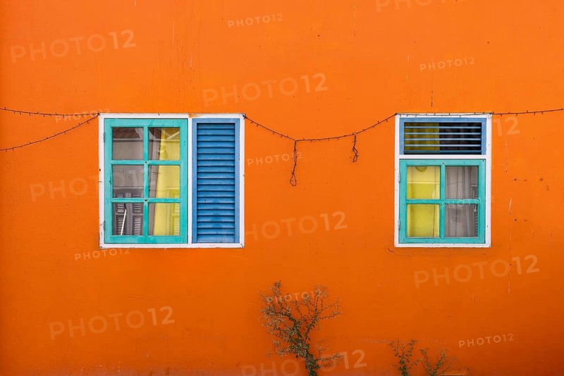 Exterior detail of a bright orange colonial building with colorful wooden shutters in Otrobanda Willemstad Curacao island