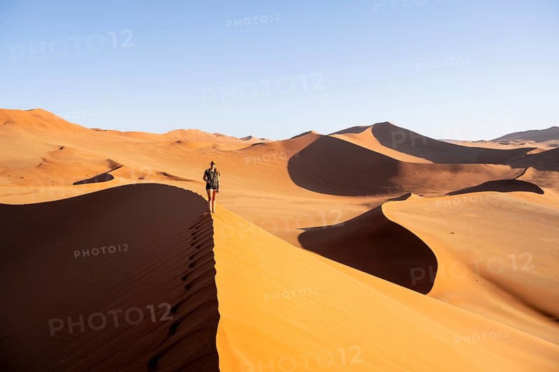 Young tourist hiking on red sand dunes, Namib, Namib Desert, Namib-Naukluft National Park, Namibia