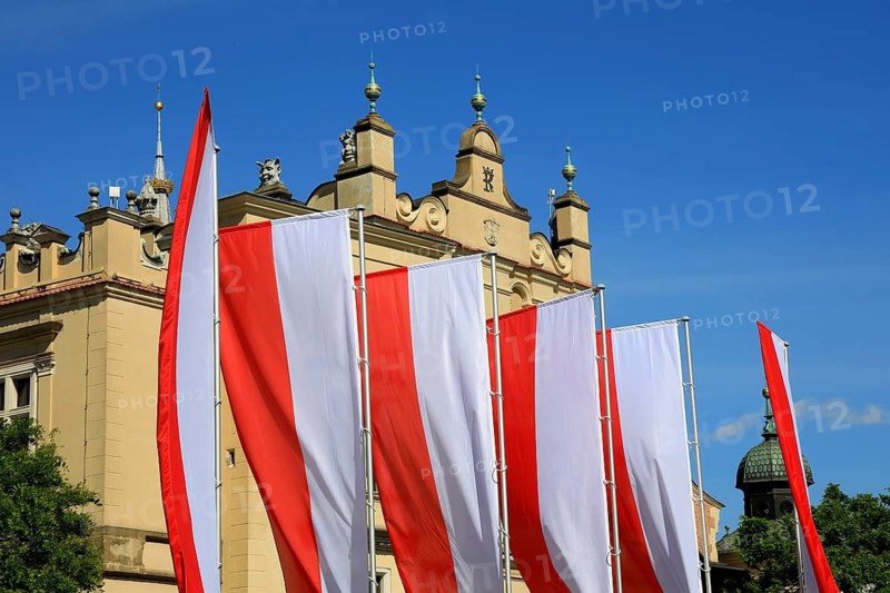 Picture shows Krakow Cloth Hall, Sukiennice, on the main market in Krakow, with vertical Polish flags in the foreground, Poland
