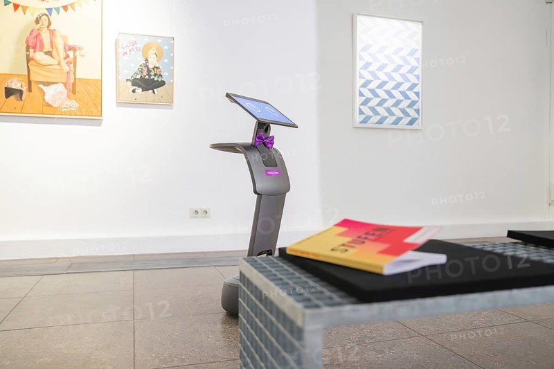 A modern robot in a gallery with works of art and a table, museum robot Robolutions, Christian Schad Museum, Aschaffenburg, Germany
