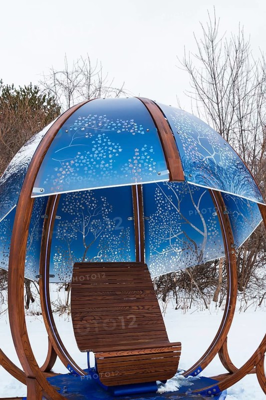 Close-up of backlit blue tinted plexiglass and curved wood panels canopy decorated with white maple leaves in the wind theme motifs inside interactive cocoon rocking chair created by Olivier Landreville, Horizon Art Installation, Ile des Moulins, Old Terrebonne, Quebec, Canada