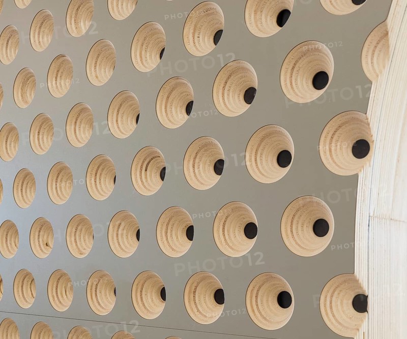 Close up of a modern club wall with a geometric design. The pattern features concentric wooden shapes with black centers, creating a stylish and textured look