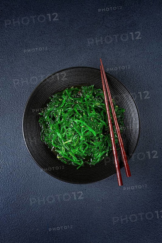 Chuka salad, made from fresh seaweed, with sesame dressing, served in a black bowl, with chopsticks