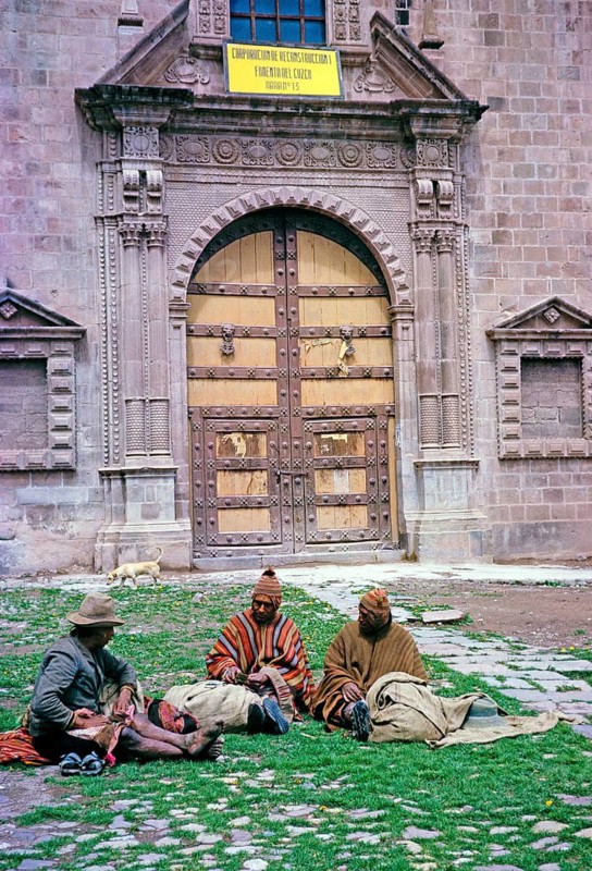 Three indigenous men sitting in front of a historic Spanish colonial building, Cuzco, Peru, South America 1962