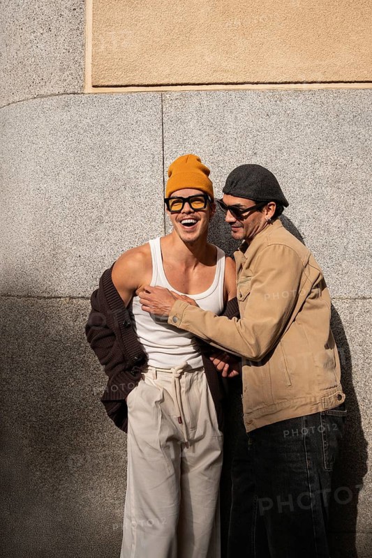 A Colombian gay couple laughing together in casual attire against an urban backdrop. Capturing warmth, joy, and connection in a relaxed setting