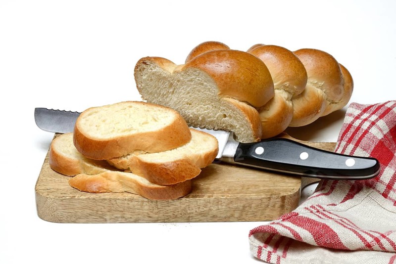 Sliced butter braid with bread knife on wooden board