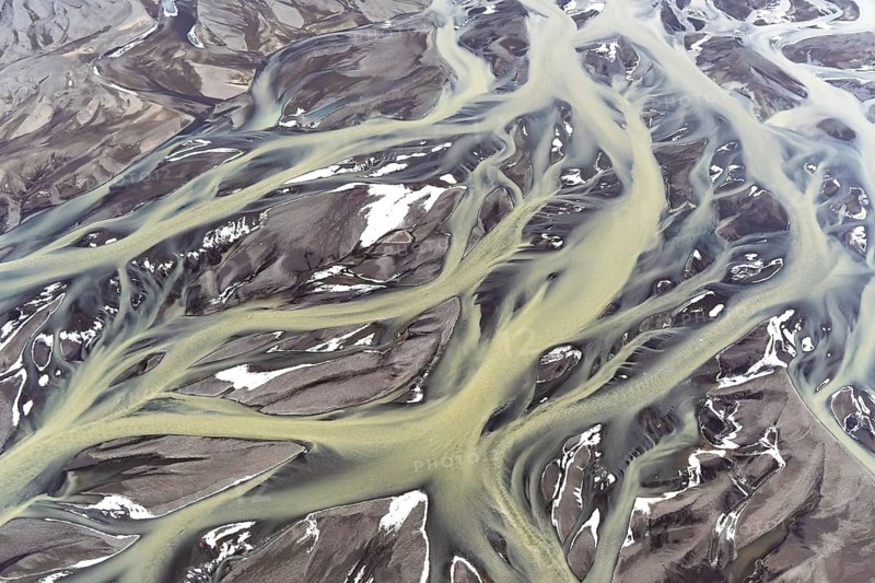 Aerial view captures the stunning golden rivers flowing through contrasting dark volcanic landscapes of Iceland, showcasing a remarkable natural palette