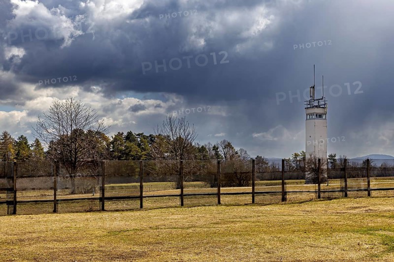 A watchtower stands behind a fence in a meadow under a cloudy sky, The Point Alpha memorial between Rasdorf and Geisa in the Rhön