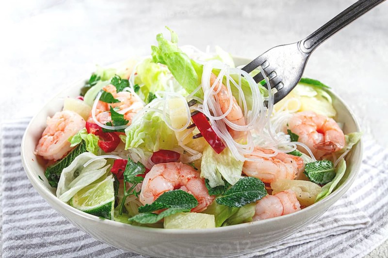 Thai salad with shrimp and rice noodles, pineapple slices, coriander and mint leaves, on a white plate, homemade, no people