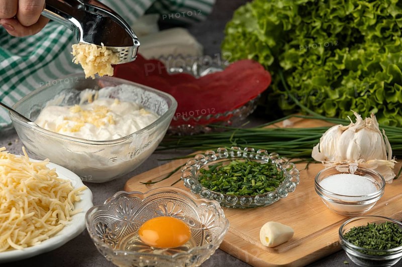 Garlic is pressed into husk with sour cream, surrounded by other ingredients such as chives, lettuce, cheese and E