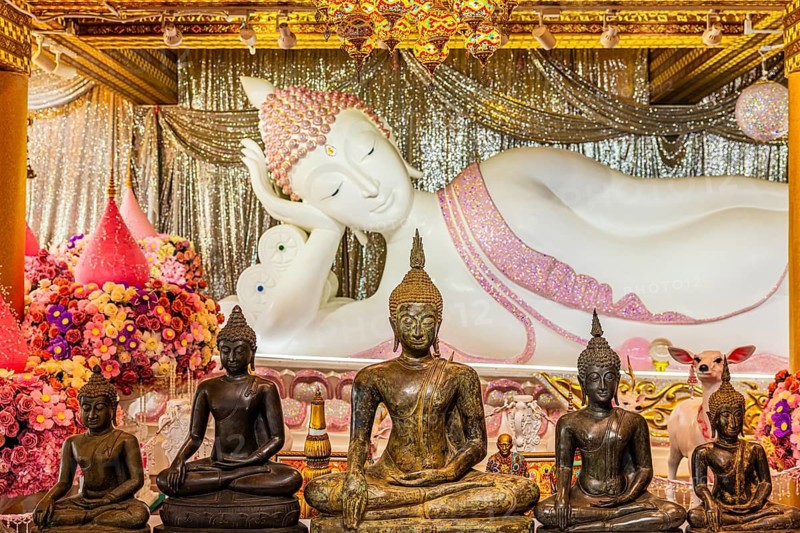Shrine with reclining Buddha statue, smaller bronze Buddha figures in front of it, Buddhist temple complex Wat Phra That Sorn Kaew, Phetchabun province, Thailand
