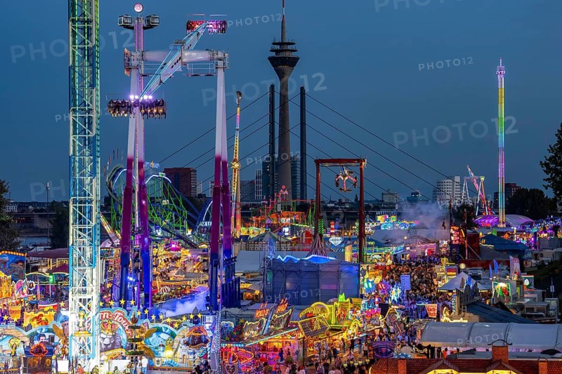 Rhine fair in the Rheinwiesen in Düsseldorf-Oberkassel, view towards the Rhine Tower, Rheinkniebrücke, rides, fairground stands, full corridors, lots of visitors, North Rhine-Westphalia, Germany