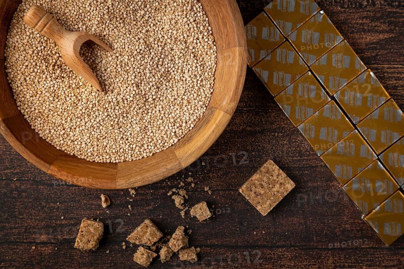 A bowl filled with quinoa next to soup cubes on a wooden table