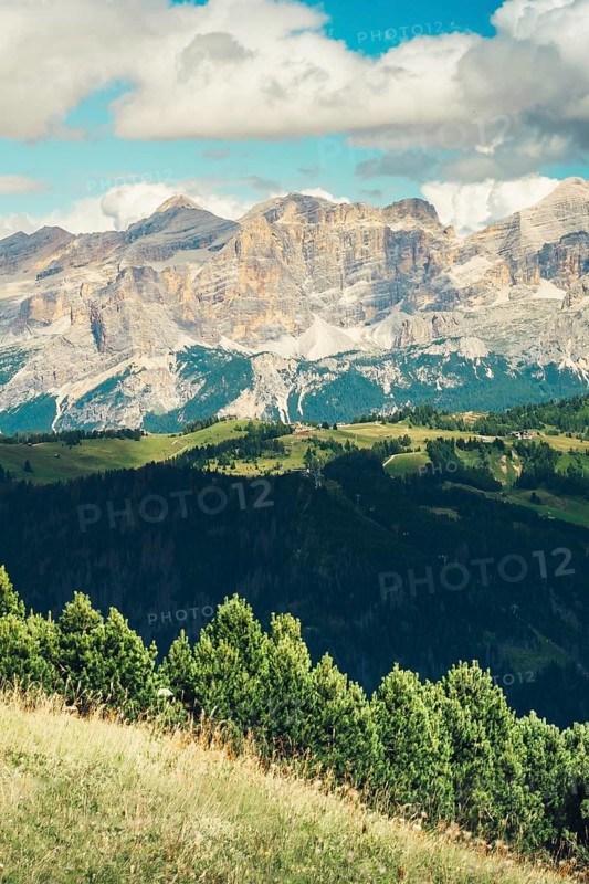 Aerial view Beautiful Dolomites mountain landscape Italy rocky jagged peaks green alpine valley meadows pine trees clouds blue sky scenic summer wilderness nature travel vista