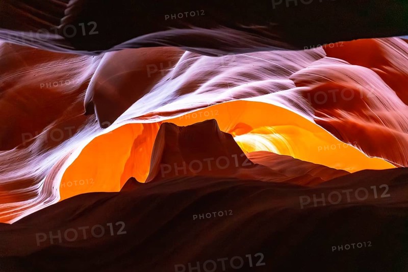 Antelope canyon slot canyon walls with flowing sandstone curves and soft light filtering narrow openings, revealing vibrant orange and purple textures and abstract eroded patterns
