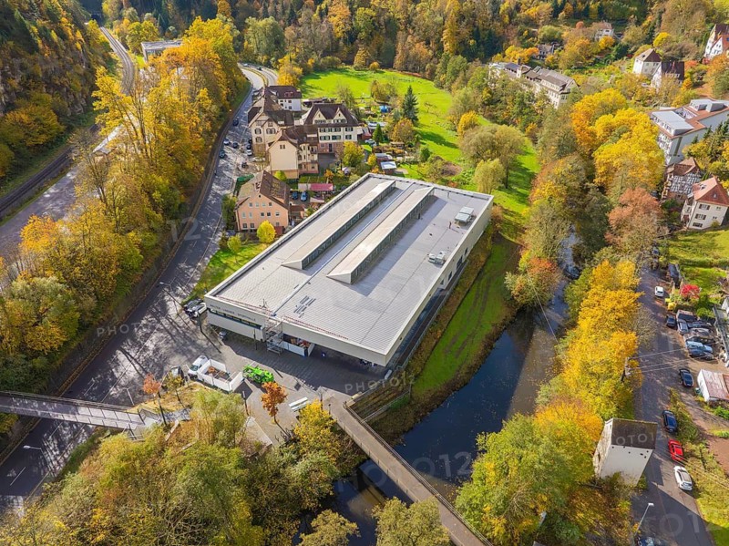 Industrial building nestled in autumnal nature near the river and neighboring residential buildings, Walther Lindner Sporthalle, Calw, Black Forest, Germany