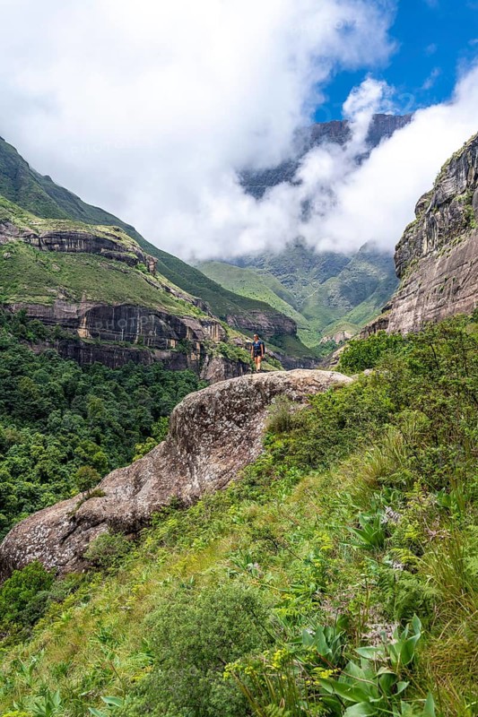 Female hiker standing in front of landscape with mountains and fog, Drakensberg National Park, KwaZulu Natal, South Africa