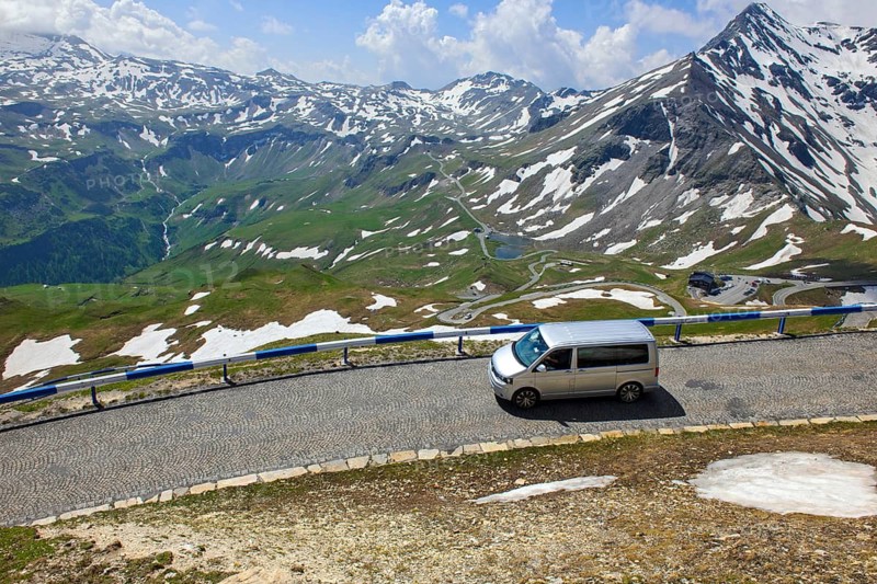 Mini-van VW bus drives on historic alpine road with cobblestones on driveway access to the Edelweisshütte on Grossglockner High Alpine Road, Fusch, State of Salzburg, Austria