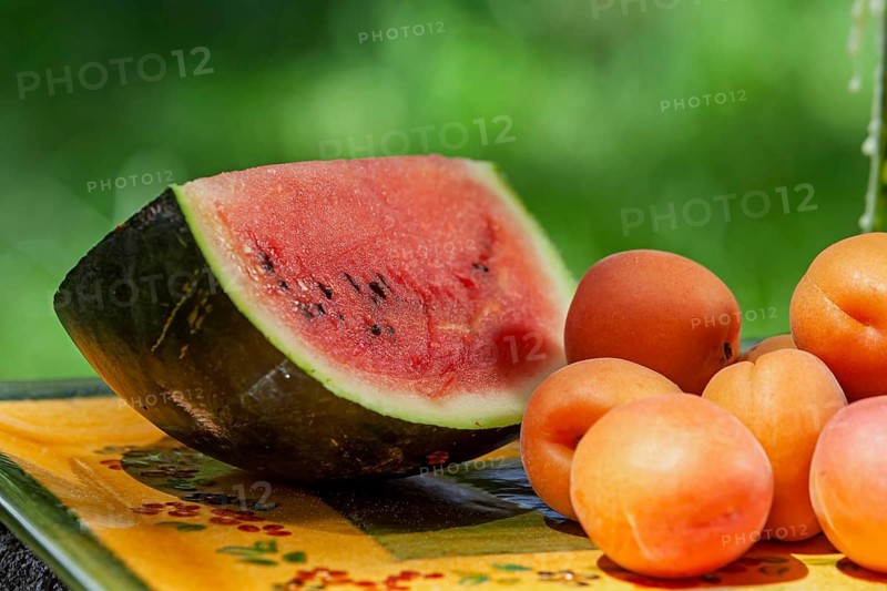 Fresh watermelon and apricots on an outdoor table with green background, Provence, France