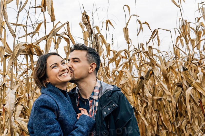 Happy couple in love in autumn in a cornfield. A man kisses a woman on the cheek