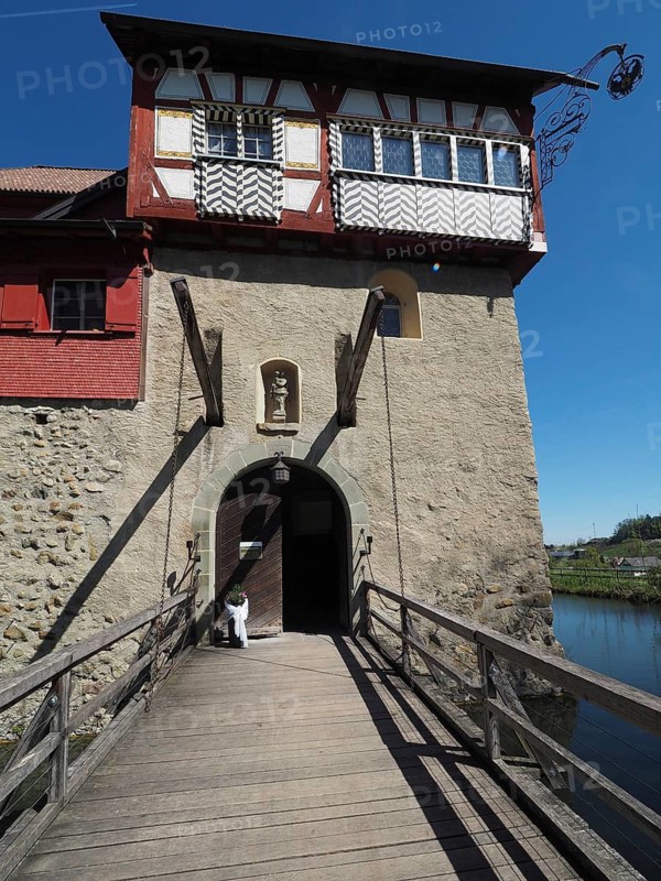 Entrance of a historic building with half-timbered elements and a drawbridge, wooden bridge under a blue sky, Hagenwil, Amriswil, Canton of Thurgau, Lake Constance region, Switzerland