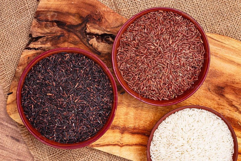Set of red and black and white rice, in a bowl, on a wooden surface, rustic style, top view