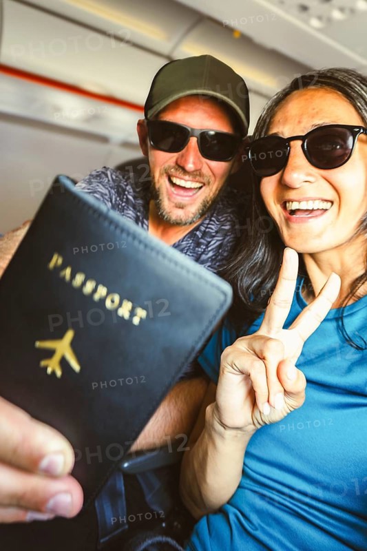 Happy young tourist couple taking selfie inside airplane - Cheerful couple on summer vacation - Passengers boarding on plane - Holidays and transportation concept