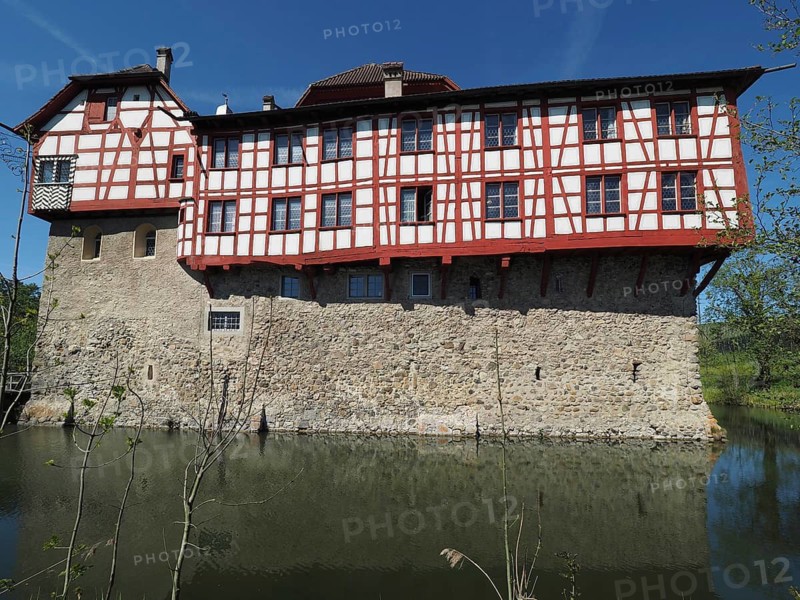 Half-timbered building in castle structure, surrounded by a moat and clear skies, Hagenwil, Amriswil, Canton of Thurgau, Lake Constance region, Switzerland