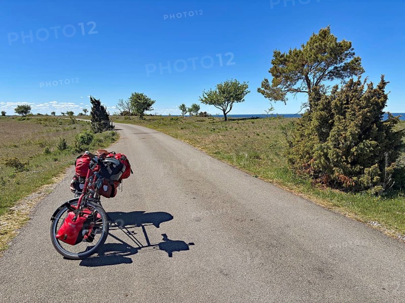 Lonely country road with parked bike and red bags under clear blue sky, cycle tourism, Sandvik, Ölandsleden, Öland, Sweden