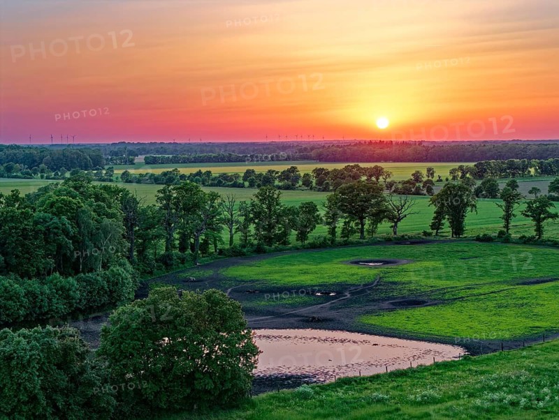 Sunset over the countryside near Dannefeld in the UNESCO Biosphere Reserve Drömling Saxony-Anhalt in the Altmark. In the foreground, pastures and a pond. aerial view. Dannefeld, Gardelegen, Saxony-Anhalt, Germany