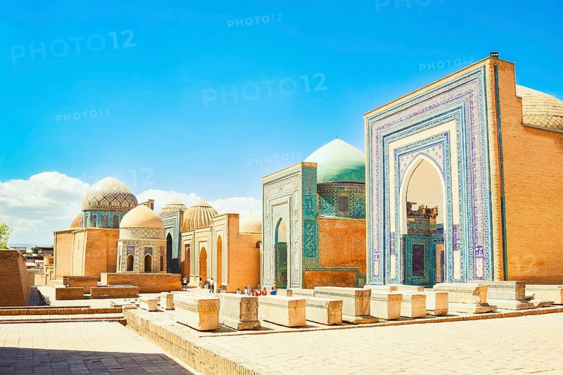 Shah i Zinda necropolis in Samarkand. Visitors explore the stunning blue-tiled mausoleums and turquoise domes of historic UNESCO Silk Road landmark