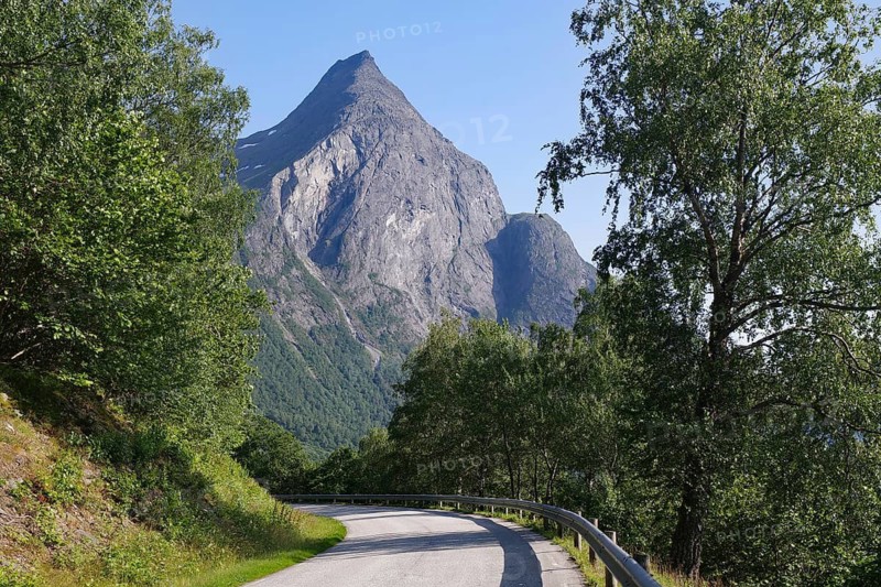 Narrow road with a view of a prominent mountain and surrounding trees, Eikesdalen, Aursjövegen, More og Romsdal, Norway