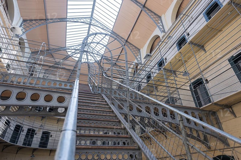 Metal staircase leads to gallery levels in an interior with domed roof and railings, Kilmainham Gaol Prison, Dublin, Ireland