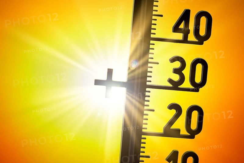 The sun shines intensely behind a thermometer that shows high temperatures, summer heat, symbolic image, heat, global warming