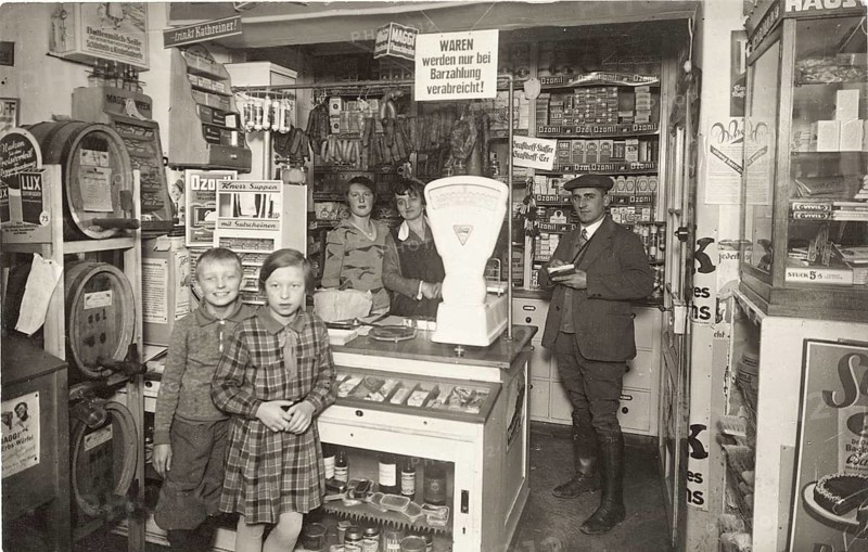 Drugstore, shop for everything, beer kegs, saleswoman, colonial goods, village shop, business, profession, twenties, a mom and pop shop with a scale and children in the foreground, surrounded by shelves, around 1920