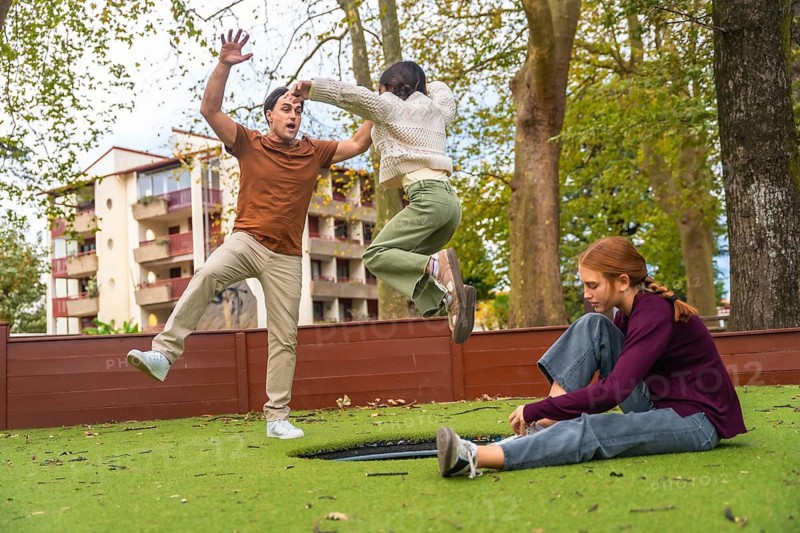 Family members, including a father and his daughters, spending quality leisure time together in an outdoor park, experiencing joy and active recreation while jumping on a trampoline
