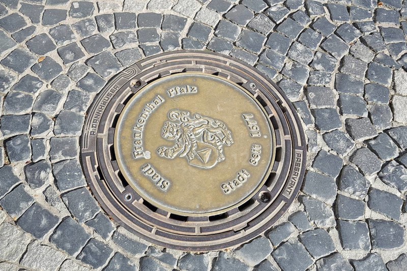 Round manhole cover with city coat of arms and date 1577 for granting city rights, inscription, casting, city history, paving stones, Frankenthal, Rhineland-Palatinate, Germany