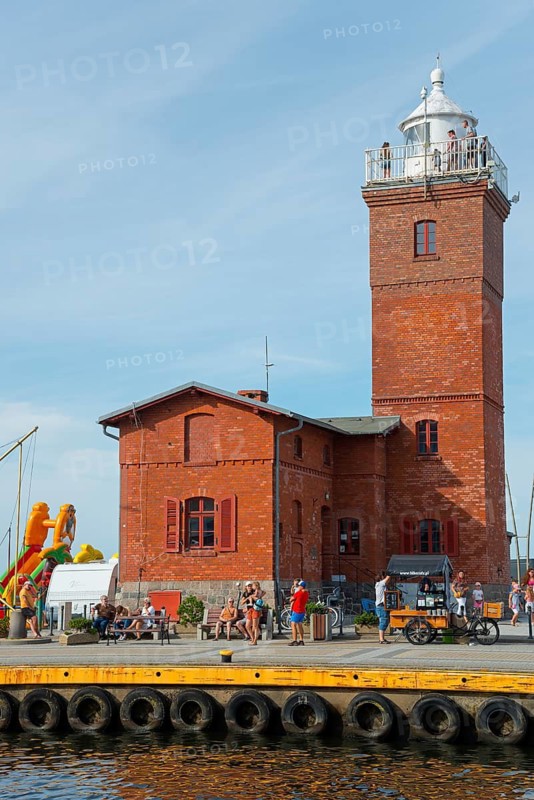 Red brick lighthouse at the harbour with people at the water, lighthouse, Darlowo, Rügenwalde, Powiat Slawienski, Schlawe, Baltic Sea, West Pomeranian Voivodeship, Poland