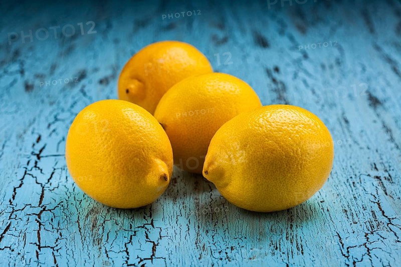 Four fresh ripe yellow lemons on blue wooden background