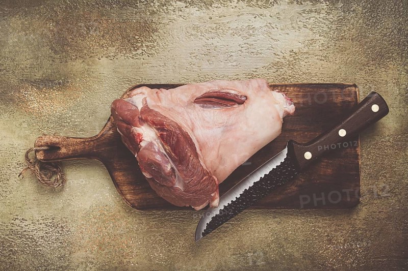 Raw pork knuckle, on a wooden chopping board, close-up, top view, no people