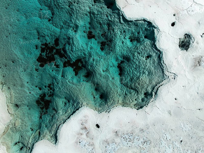 An aerial view of the vibrant salt ponds in La Puna, Argentina, showcasing striking turquoise and white contrasts. This landscape captures the unique beauty and texture of the region