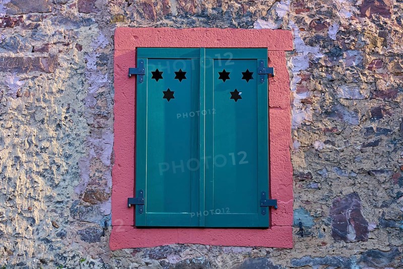Green shutters with star patterns on a stone wall, Erbach, Odenwald, South Hesse, Hesse, Germany