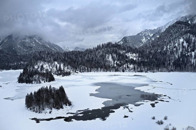 Ice-covered and snow-covered lake in wintry mountain landscape, cloudy, snow-covered trees, Dreiseen area, Chiemgau, Bavaria, Germany