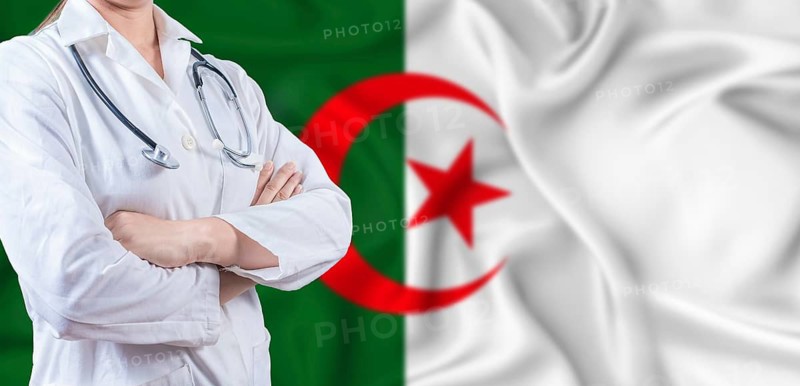 Doctor with crossed arms on Algeria flag. Algerian health and care concept. Female doctor on Algeria flag