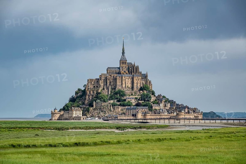View over lush green salt marshes to the rocky island, Le Mont Saint Michel monastery island with the former Benedictine abbey in Norman style, tourist attraction, UNESCO World Heritage Site, Pontorson, Manche department, Normandy, France