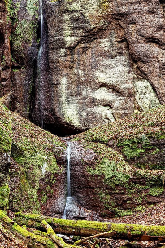 A gentle waterfall cascades down from a rough rock and reinforces the quiet, natural environment, The Dragon Gorge near Eisenach in Thuringia