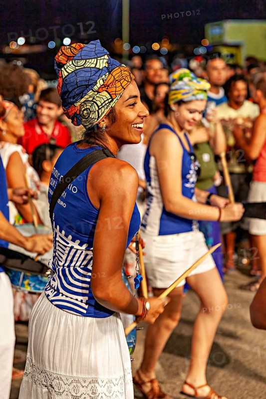 Woman with colorful headscarf dancing laughing with drum at night, joy and dancing at a festival in Petrolina in Brazil
