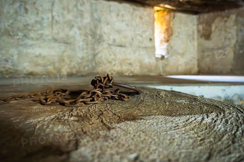 Close-up of authentic iron chains and shackles display in underground slave chamber in Mkunazini, Zanzibar. Somber historic artifact in a dimly lit Stone Town dungeon