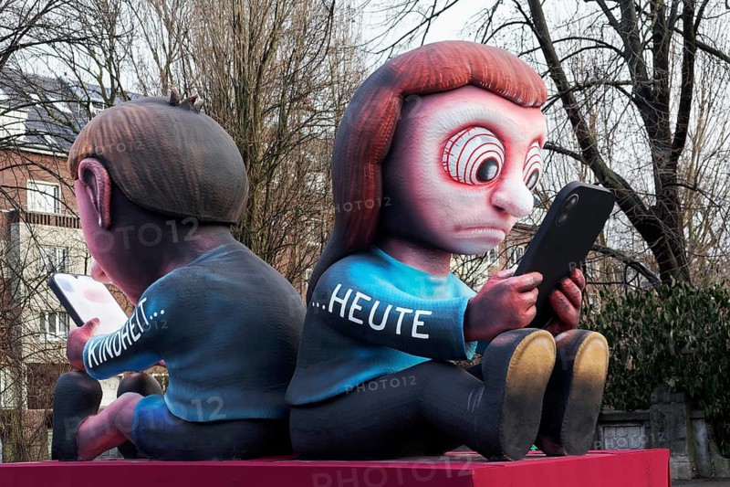 Two young people stare at the cell phone, childhood today, social media addiction, theme car by wagon maker Jacques Tilly, Düsseldorf Rose Monday train, Düsseldorf, North Rhine-Westphalia, Germany