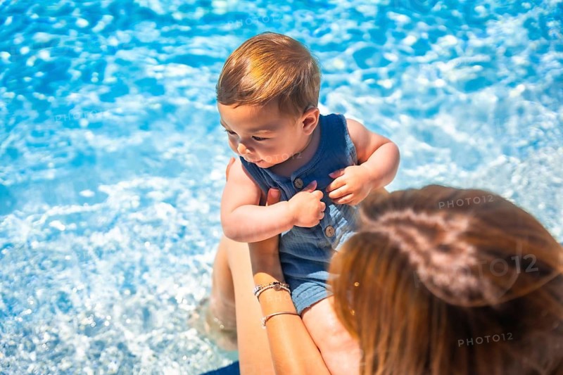 Top view close-up of a caucacsian mother holding a baby on a swimming pool